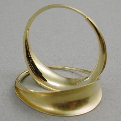 E-10: These 18 karat gold hoop earrings are made using a technique called "Anticlastic Raising". The entire earring is made from a sheet of gold that is formed with a hammer. One end is hammered into a small tube that receives the other end that has been hammered into a small wire. Few people own earrings that require so many hours to make. For more information please call: (307) 382-3195