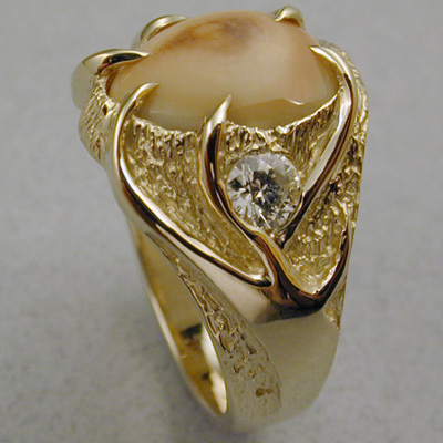 ER-8: This Elk Ivory ring looks a bit like Elk Antlers are holding the ivory in place. Two quarter carat diamonds were used as accents. One on each side. For more information please call: (307) 382-3195