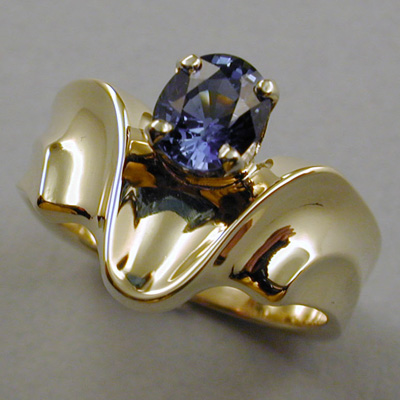 R-13: An oval three quarter carat blue sapphire is showcased in this 18 karat gold design. For more information please call: (307) 382-3195