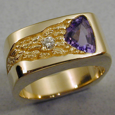 R-26: The Tanzanite in this ring is a show stopper and is accented with a 5 point diamond. You will be guaranteed many admiring glances wearing this ring. Eighteen karat gold and the nugget texture exude a warm rich color that stands in stark contrast to the Tanzanite. For more information please call: (307) 382-3195