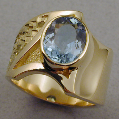 R-9: A heavier 18 karat gold design using a bezel set Aquamarine as accent. For more information please call: (307) 382-3195